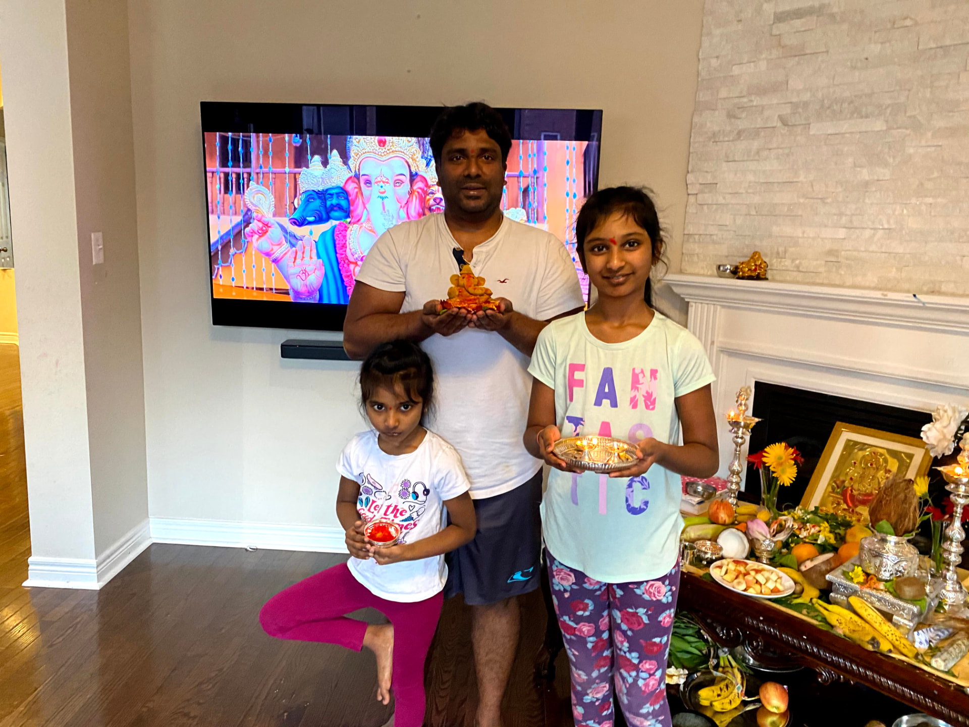 Family celebrating Ganesh Pooja at home with a virtual gathering on screen, 2020