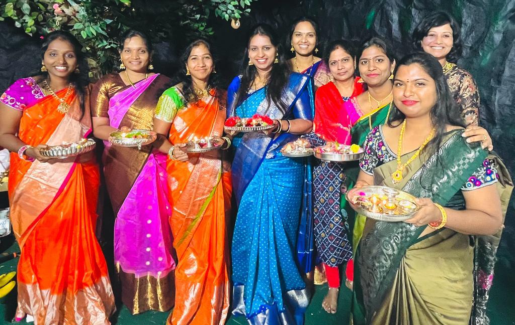 Women holding plates of offerings before the decorated Ganesh mandap, 2023