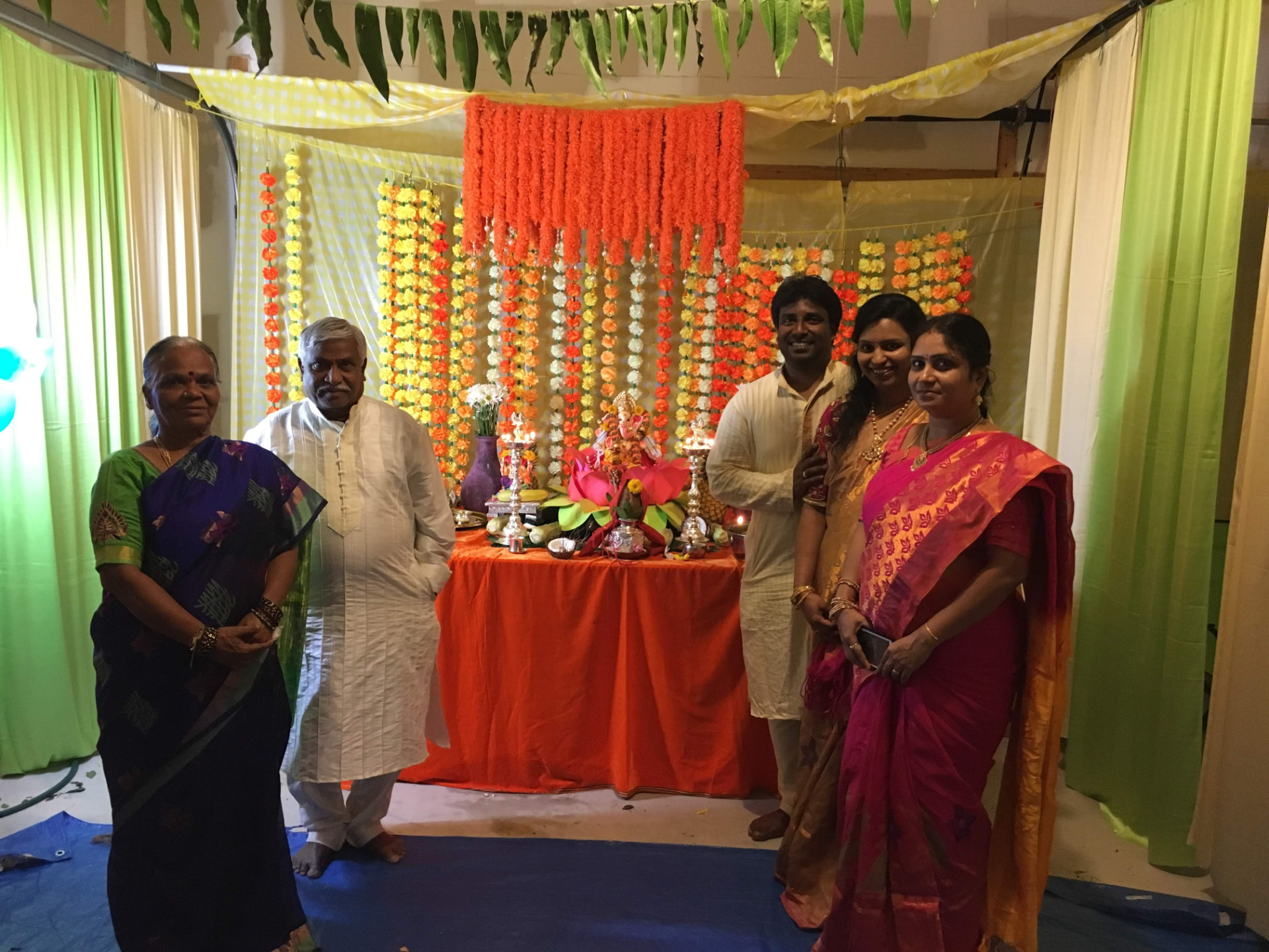 Family posing with the Ganesh idol and marigold backdrop, 2017