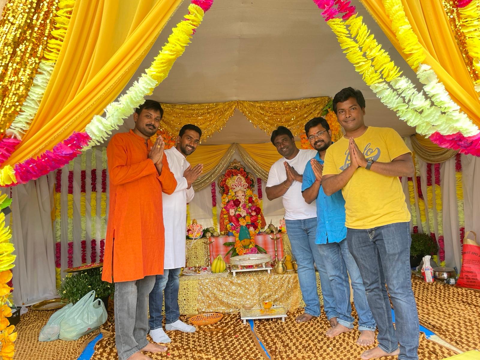 Group of community members praying together inside a brightly decorated Ganesh mandap, 2021