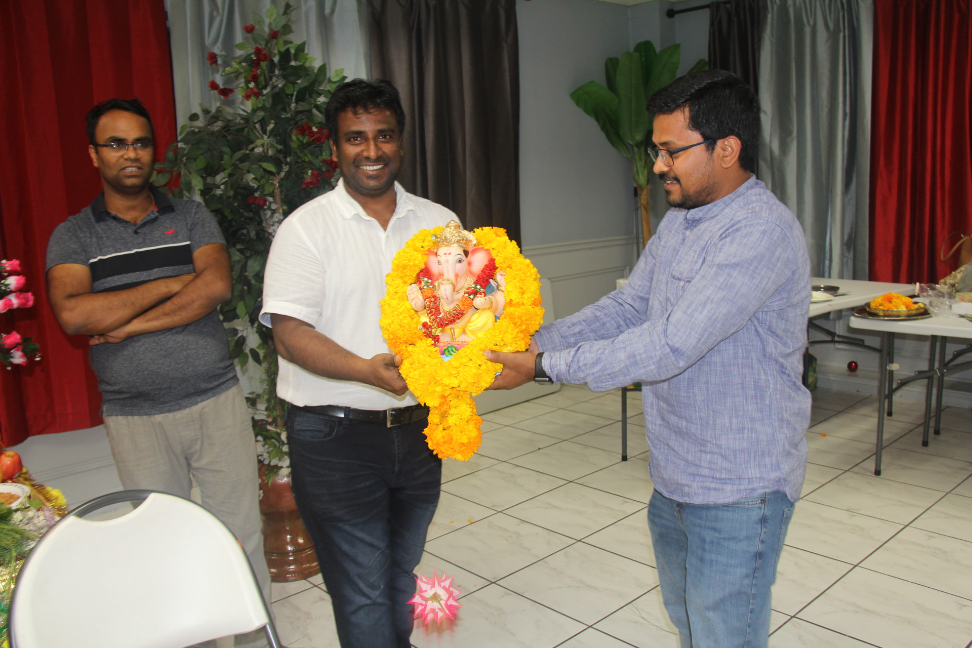 Friends welcoming the Ganesh idol adorned with a marigold garland, 2018
